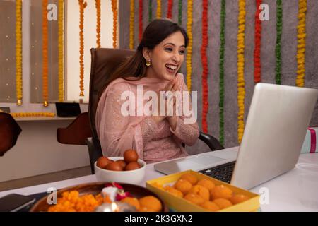 Frau mit Videoanruf auf dem Laptop im Büro während der Diwali-Feier Stockfoto