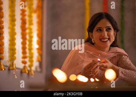 Frau dekoriert Büro, indem sie Diyas auf den Tisch anlässlich der Diwali Stockfoto