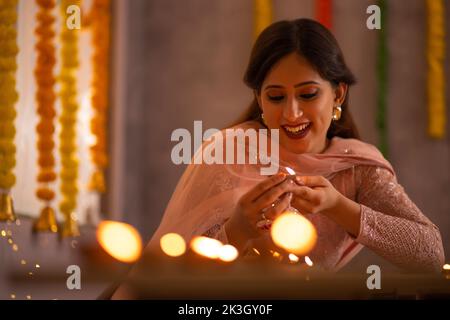 Frau dekoriert Büro, indem sie Diyas auf den Tisch anlässlich der Diwali Stockfoto