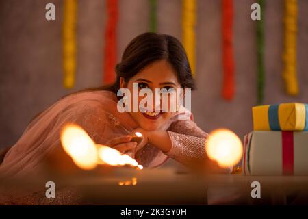 Frau dekoriert Büro, indem sie Diyas auf den Tisch anlässlich der Diwali Stockfoto