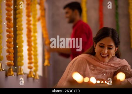 Frau dekoriert Büro, indem sie Diyas auf den Tisch anlässlich der Diwali Stockfoto