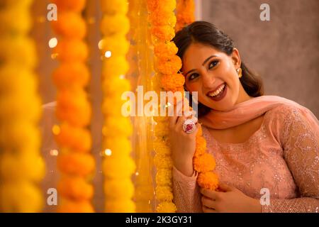 Frau, die das Büro mit Blumengirlande anlässlich der Diwali schmückt Stockfoto