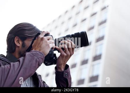 Die Schönheit, die ihn umgibt, einfangen. Ein junger Mann, der mit seiner Kamera ein Foto gemacht hat. Stockfoto