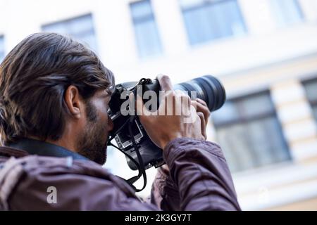 Die Schönheit, die ihn umgibt, einfangen. Ein junger Mann, der mit seiner Kamera ein Foto gemacht hat. Stockfoto