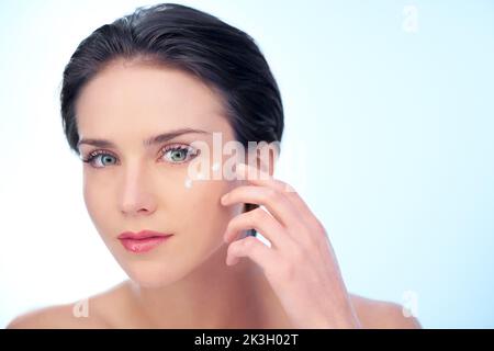 Anti-Aging beginnt jetzt. Eine junge Frau, die Lotion auf ihr Gesicht auftragen. Stockfoto