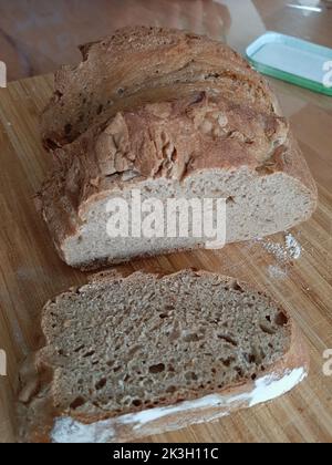 Frisches, hausgemachtes Brot in Scheiben geschnitten auf einem Holzbrett Stockfoto