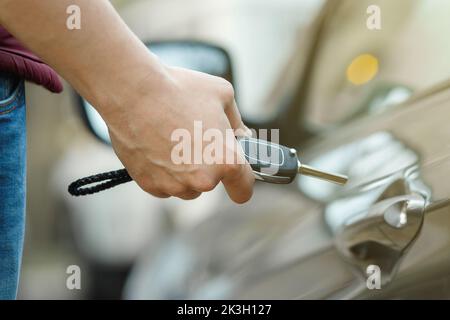 Ein Mann öffnet mit einem Schlüssel und einer Nahaufnahme eine Tür zur Autovermietung Stockfoto