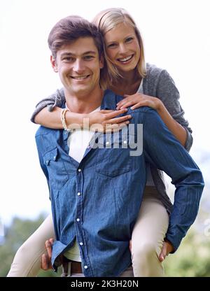 Verspielter Huckepack. Eine junge Frau erhält von ihrem Freund eine Huckepack-Fahrt. Stockfoto