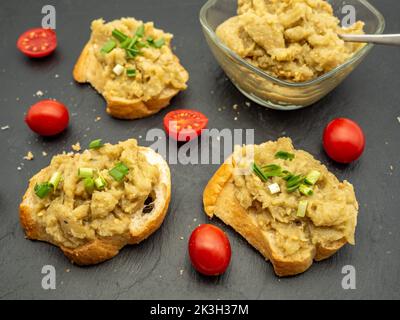 Vorspeise rumänischer Auberginen-Salat mit Zwiebeln und Tomaten auf Brot verteilt Stockfoto