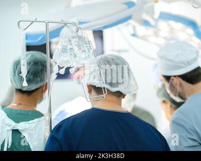Moskau. Russland. 22. September 2022. Selektiver Fokus auf transparente Plastiktüten von medizinischen Tropfern im Operationssaal. Chirurgen vor unscharfem Hintergrund. Stockfoto
