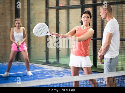 Paddle-Tennislehrerin erklärt Anfängern, wie man Schläger hält Stockfoto