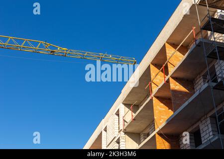 Isolierung der Außenwände eines Gebäudes im Bau. Die Wände des im Bau befindlichen Gebäudes sind von Gerüsten für Arbeiten umgeben Stockfoto