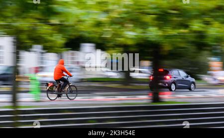 Hannover, Deutschland. 27. September 2022. Am frühen Morgen fährt ein Mann mit dem Fahrrad neben einem Auto durch die Innenstadt. Quelle: Julian Stratenschulte/dpa/Alamy Live News Stockfoto