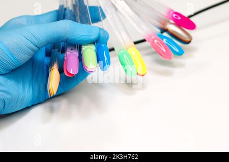 Master Manikurist im Nagelstudio bietet Farbe des Nagellacks für weibliche Klientin. Auswahl der festgelegten Farbe der Gelpolitur für die Anwendung Maniküre auf Frau Client n Stockfoto