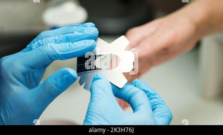 Konstruktion von Schönheitsnägeln. Untere Nagelverlängerung. Master Manikurist im Schönheitssalon hält eine Papierform für Nagelverlängerung. Maniküre. Fingernägel Stockfoto