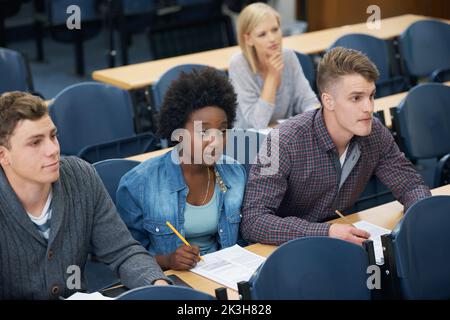 In allen Informationen vor den Prüfungen. Eine Gruppe von Studenten in ihrem Vortrag, die Notizen machen und aufpassen. Stockfoto