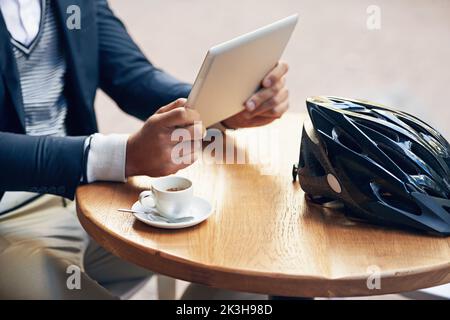 Ein Geschäftsmann, der sein digitales Tablet benutzt, während er in einem Café im Freien Kaffee getrunken hat. Stockfoto