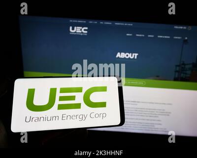 Person, die ein Smartphone mit dem Logo des US-Bergbauunternehmens Uranium Energy Corp. (UEC) auf dem Bildschirm vor der Website hält. Konzentrieren Sie sich auf die Telefonanzeige. Stockfoto