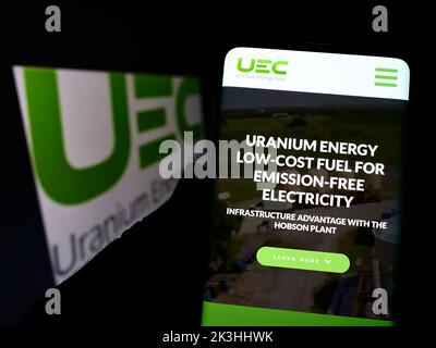 Person mit Smartphone und Website des Bergbauunternehmens Uranium Energy Corp. (UEC) auf dem Bildschirm mit Logo. Konzentrieren Sie sich auf die Mitte des Telefondisplays. Stockfoto