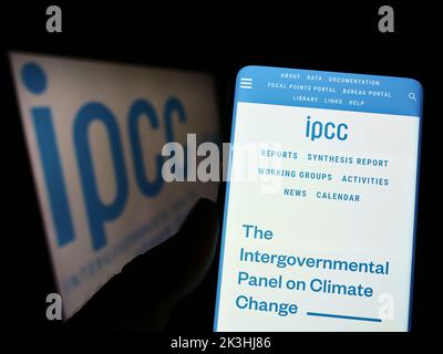 Person mit Mobiltelefon und Website des Intergovernmental Panel on Climate Change (IPCC) auf dem Bildschirm mit Logo. Konzentrieren Sie sich auf die Mitte des Telefondisplays. Stockfoto