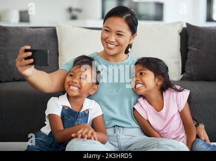 Selfie, Familie und Kinder mit einem Mädchen, einer Tochter und einer Pflegemutter, die im Wohnzimmer des Hauses ein Foto machen. Kinder, Liebe und Zuneigung mit einem Stockfoto