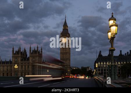 Dämmerungsbild von Houses of Parliament und Elizabeth Tower mit beweglichen Londoner Bus- und Straßenlaternen. Beweglicher Bus mit Geisterbild Stockfoto