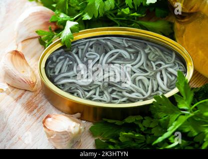 Eingelegte Aale in offener Dose mit Knoblauch am Tisch Stockfoto