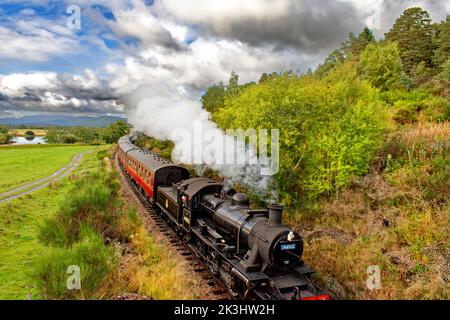 STRATHSPEY DAMPFEISENBAHN AVIEMORE SCOTLAND ZUG NÄHERT SICH BROOMHILL STATION FLUSS SPEY UND CAIRNGORMS IM HINTERGRUND Stockfoto