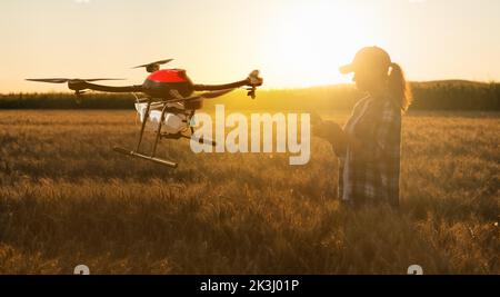 Frau Farmer kontrolliert die Drohnenspritze mit einer Tablette. Intelligente Landwirtschaft und präzise Landwirtschaft Stockfoto