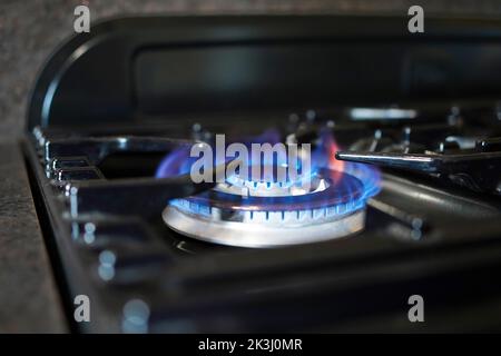 Das Kochen mit Gas wird schwierig, da die Lebenshaltungskosten auf katastrophalem Niveau steigen. Nationale Energiekrise. Blaue Flamme auf einem Gasring des Herdes. Stockfoto