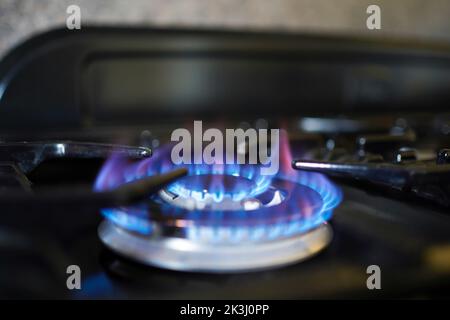 Das Kochen mit Gas wird schwierig, da die Lebenshaltungskosten auf katastrophalem Niveau steigen. Nationale Energiekrise. Blaue Flamme auf einem Gasring des Herdes. Stockfoto