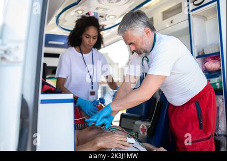 Ärzte im Krankenwagen, die eine kardiopulmonale Reanimation an einem kritischen Patienten durchführen Stockfoto