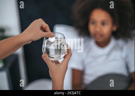 Nettes Mädchen reden eine lösliche Pille, während sie krank Stockfoto