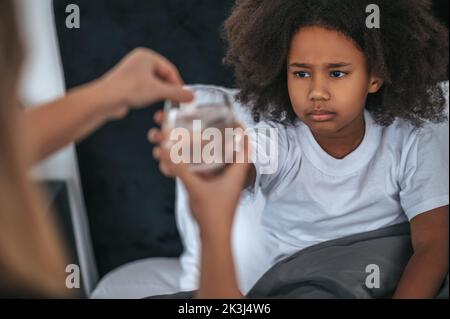 Nettes Mädchen reden eine lösliche Pille, während sie krank Stockfoto