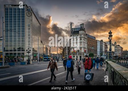 Dublin, 2019. November am frühen Morgen, Sonnenaufgang, auf der geschäftigen OConnell Bridge mit Blick auf das National Wax Museum. Luas und Bushaltestelle oder Drehkreuz auf der Westmoreland St. Stockfoto