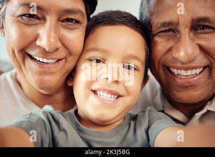 Junge machen Selfie mit glücklichen Großeltern, zusammen in Nahaufnahme oder Zoom-Porträt im Haus. Latino männliches Kind lächelt mit Oma und Opa im Makro mit Stockfoto