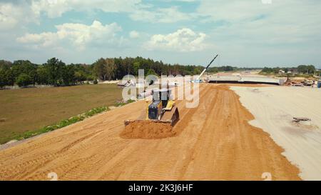 Oberflächengitter. Eine Planierraupe bewegt den Boden mit einem befestigten Blatt auf einer Baustelle. Warschau, Polen. Hochwertige Fotos Stockfoto