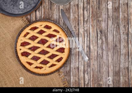 Draufsicht auf hausgemachten Kuchen namens 'Linzer Torte', ein traditionelles österreichisches Shortcake-Gebäck mit Obstkonserven und gemahlenen Nüssen mit Gitterdessig Stockfoto