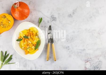 Saisonales Herbstrezept. Kürbisravioli mit Salbei, Parmesan und Olivenöl. Stockfoto