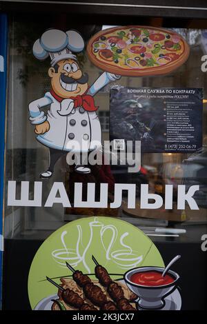 Woronesch, Russland - 26. September 2022, Ankündigung des Militärdienstes im Rahmen eines Vertrags auf einem Fenster mit der Aufschrift "Schaschlik" während der Mobilisierung in Woronesch. Am 21. Februar unterzeichnete der russische Präsident Wladimir Putin ein Dekret über die sogenannte Teilmobilisierung. Diesem Dokument zufolge können fast alle Männer im Alter von 18 bis 65 Jahren zum Militärdienst aufgerufen werden. Einige dieser Menschen können direkt in den Krieg mit der Ukraine geschickt werden. Neben Protesten gegen die Mobilisierung begrüßten viele russische Bürger dieses Dekret mit Begeisterung. In Woronesch, fast jeden Tag, versammeln sich die Gruppen der Menschen in der Milit Stockfoto