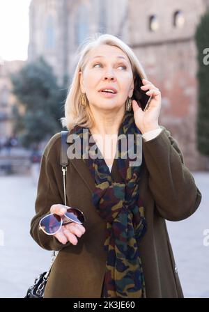 Erwachsene Frau spricht über das Telefon mit Freund auf der Straße im Freien Stockfoto