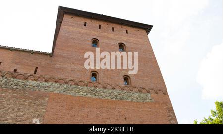 Ein alter großer Burgturm mit kleinen roten Ziegelfenstern. Historisches Gebäude aus dem 14.. Jahrhundert, Konstruktion Stockfoto