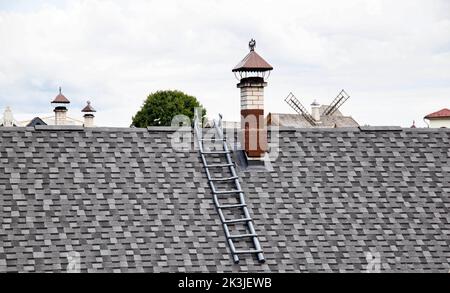 Schindeldach. Alte Methode der Herstellung von Dächern aus Holz, Hintergrund. Dachleiter und Kamin Stockfoto