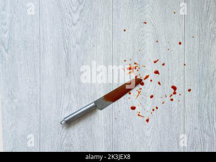 Die Klinge des Messers im Blut liegt auf dem Boden. Messer und Verletzungen, Verbrechen. Stockfoto