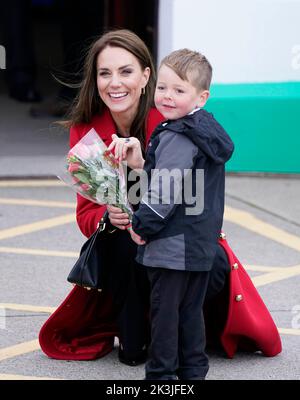 DIE Prinzessin von Wales erhält von der vierjährigen Theo Crompton eine schicke Blumenpracht, als sie zu einem Besuch der RNLI Holyhead Lifeboat Station in Holyhead, Wales, eintrifft, wo sie mit dem Prinz von Wales die Crew trifft, Freiwillige und einige von denen, die von ihrer lokalen Einheit unterstützt wurden. Holyhead ist eine der drei ältesten Rettungsbootstationen an der walisischen Küste und hat eine bemerkenswerte Geschichte der Tapferkeit, da sie 70 Auszeichnungen für die Galanterie erhalten hat. Bilddatum: Dienstag, 27. September 2022. Stockfoto