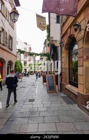 Menschen, die durch eine enge Fußgängerzone gehen, an Geschäften und Restaurants vorbei, im Quartier des Tonnélions, Straßburg, Frankreich. Stockfoto