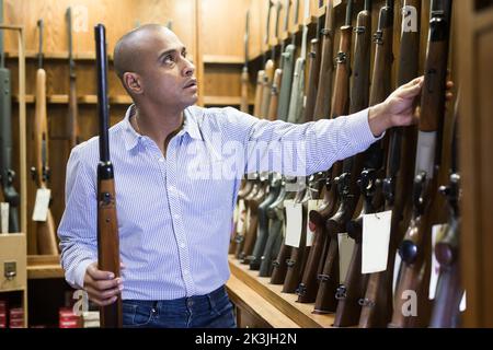 Porträt eines selbstbewussten Mannes in der Waffenhandlung mit Gewehr Stockfoto
