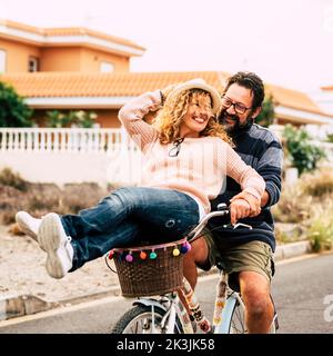 Zwei glückliche und aktive Person Mann und Frau genießen Fahrradtour zusammen Spaß haben und viel lachen. Junge ältere Paare verwenden grünen Öko-Transport. Männlich Stockfoto