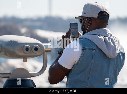 Junger Mann besucht die Niagarafälle in Kanada. Tourist, der im Urlaub 2022 mit einem Handy Bilder von den Wasserfällen macht. Stockfoto