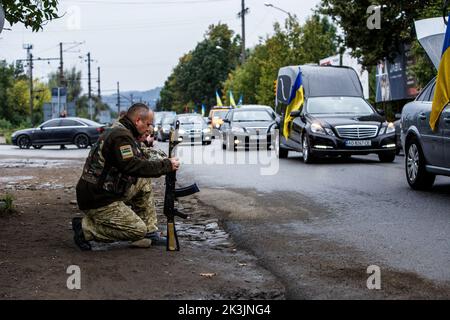 PERECHYN, UKRAINE - 25. SEPTEMBER 2022 - Soldaten knien, um dem Oberleutnant Armen Petrosian, 50, der während der Liberati starb, ihre letzte Ehre zu erweisen Stockfoto